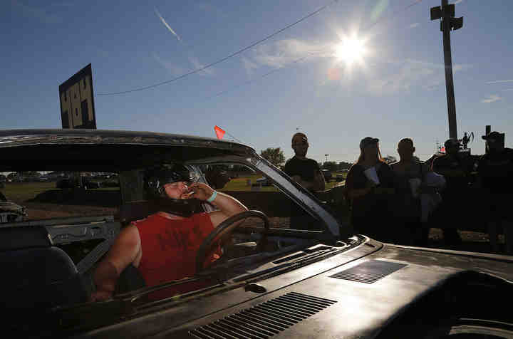 Philip Elson of Port Jefferson takes a drag of his cigarette before driving into the arena for the full street stock category during the Logan County Fair demolition derby in Bellefontaine.  (Adam Cairns / The Columbus Dispatch)